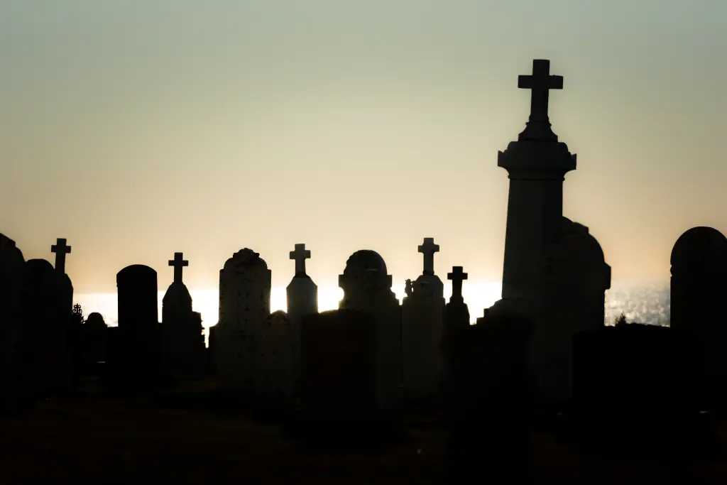 An evening sky with gravestones in silhouette against it